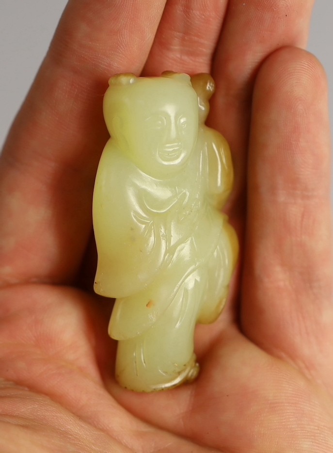 A rare Chinese yellow and russet jade figure of a boy holding a parrot, 18th/19th century, 5.6cm high, wood stand